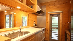 Una cocina moderna con armarios de madera, electrodomésticos de acero inoxidable y un amplio ventanal que proporciona luz natural.
