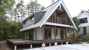 Una casa moderna con techo inclinado, terraza de madera y ventanas amplias.