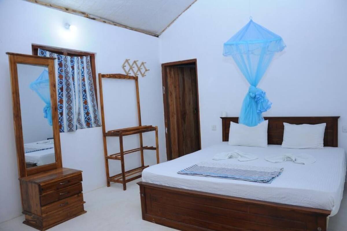 A bedroom with a wooden bed, a wooden dresser, a mirror, and a blue canopy.