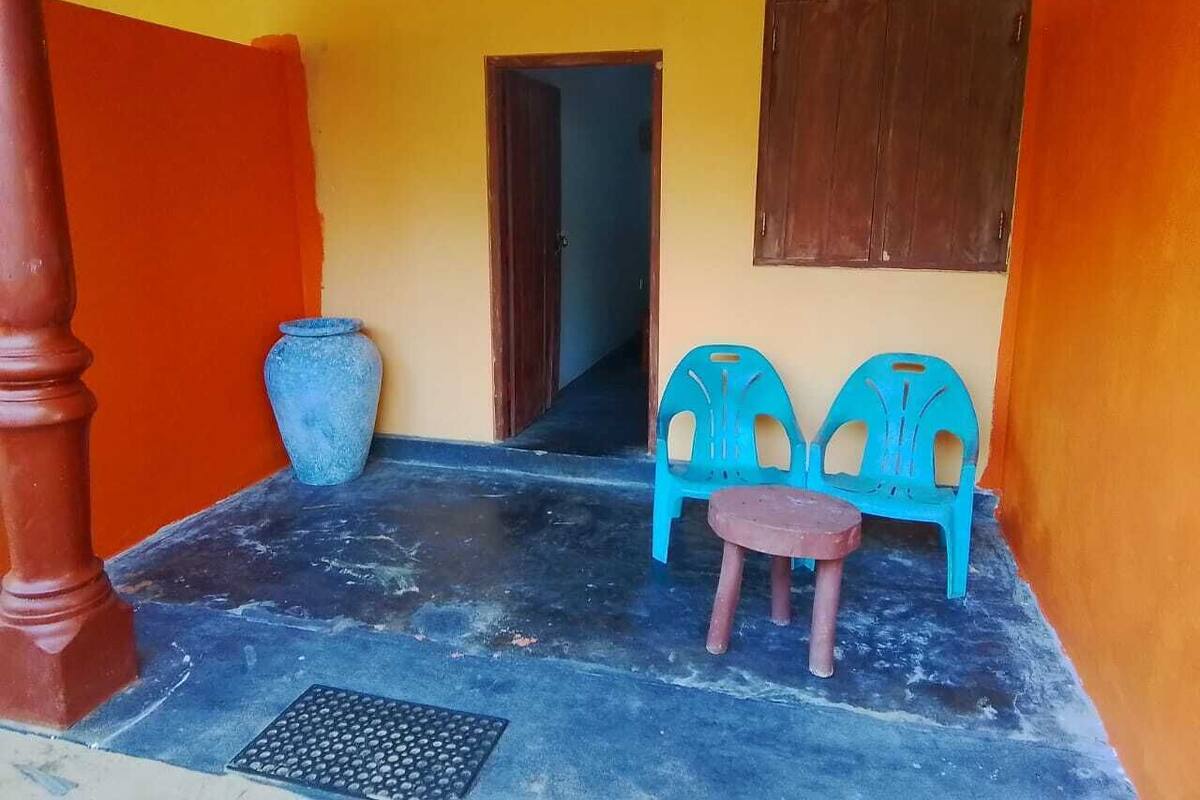 A small, enclosed outdoor area with a tiled floor, a wooden door, and two blue plastic chairs.