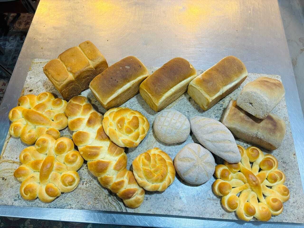 A variety of bread rolls displayed on a metal tray.