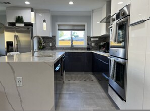 A modern kitchen with stainless steel appliances, a built-in oven, and a large window. - Upscale Modern 4BR Torrance House Built 2018 w Garage Fenced Yard Patio p79 (Torrance)
