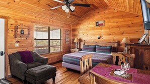Una cabaña acogedora con cama, sillón, mesa de comedor y ventilador de techo.