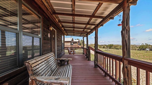 Un porche de madera con un banco, una mesa y vistas del paisaje.
