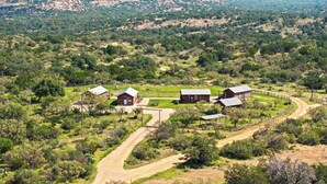 A rural property with multiple cabins, a dirt road, and a hilly landscape in the background.