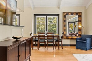 Un coin repas avec une table et des chaises en bois, un buffet en bois foncé et un grand miroir au mur.