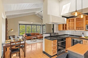 Une cuisine moderne dotée d’un îlot central, d’appareils électroménagers intégrés et de meubles de rangement en bois.