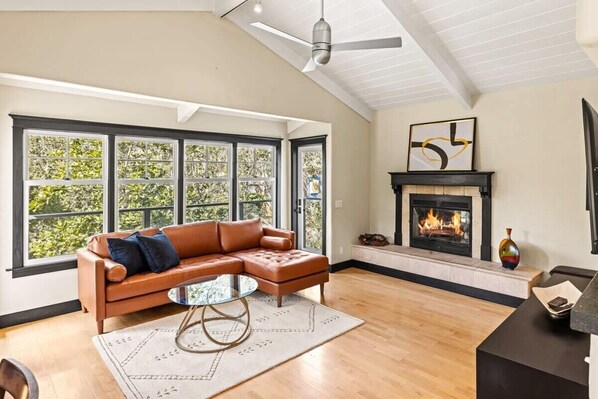 A modern living room with a leather sectional sofa, a glass coffee table, and a fireplace.