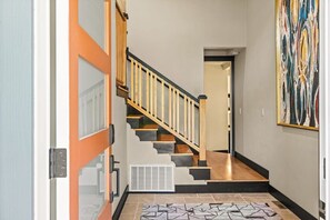 Un couloir avec un escalier, un radiateur et un tapis à motifs.