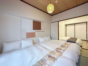 A bedroom with a large bed, a hanging light fixture, and a sliding door closet. - Dai3kuboi 305 (Hiroshima)