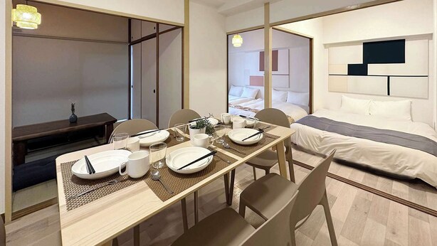 Ein modernes Hotelzimmer mit Essbereich, einem Bett mit Kopfteil und einem begehbaren Kleiderschrank.