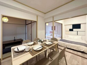 A modern hotel room with a dining area, a bed with a headboard, and a walk-in closet. - Dai3kuboi 305 (Hiroshima)