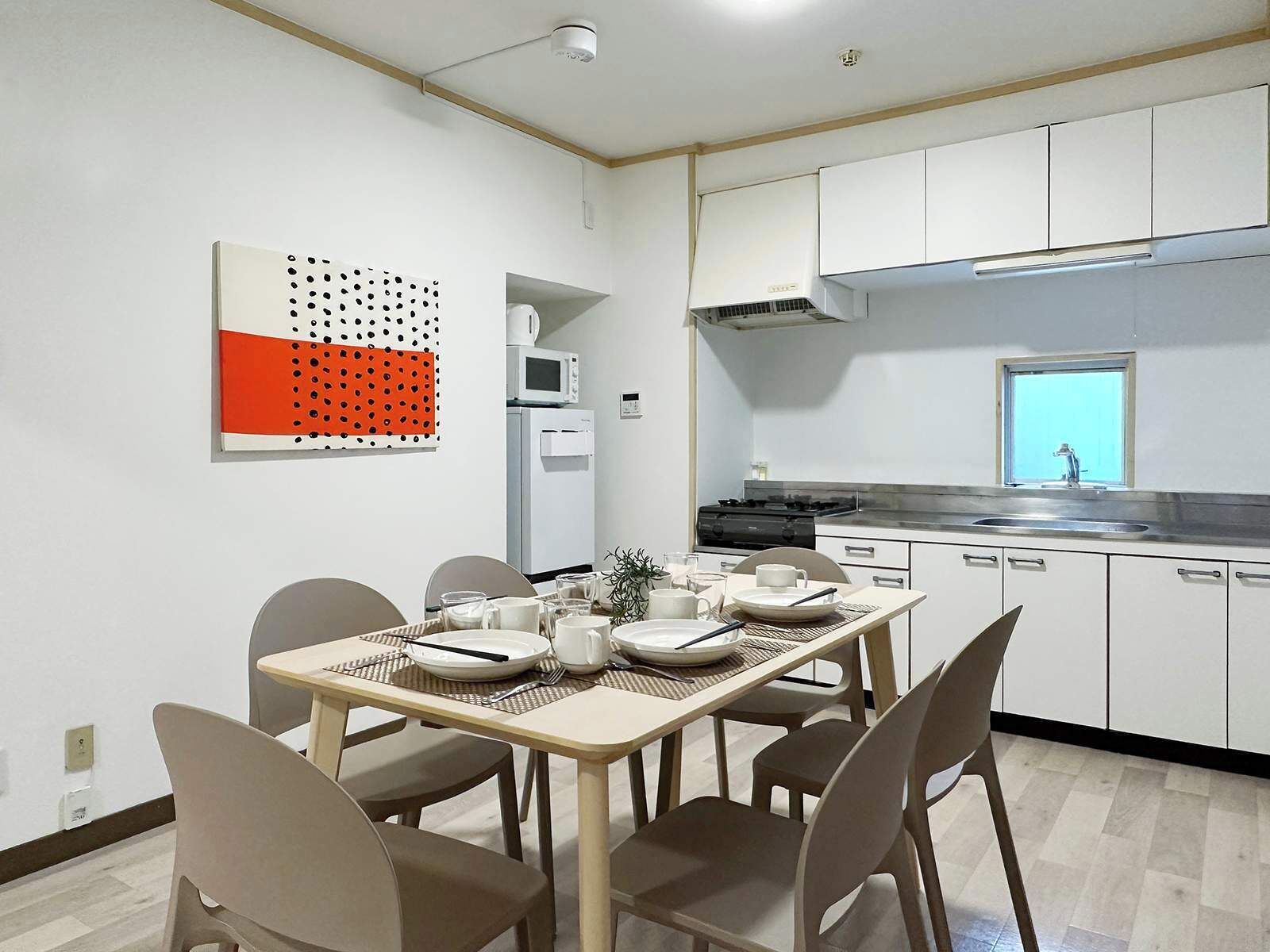 Una cocina moderna con armarios blancos, una estufa y un microondas. Hay una mesa de comedor con sillas y un adorno en la pared.