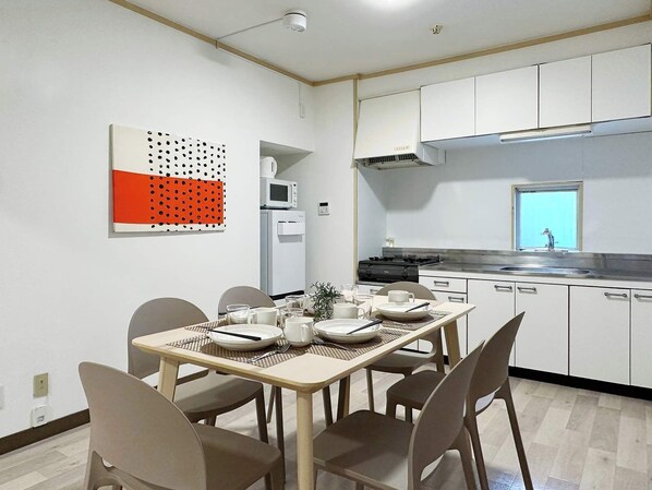 Une cuisine moderne avec des armoires blanches, une cuisinière et un four à micro-ondes. On y trouve une table à manger avec des chaises et un élément décoratif mural.