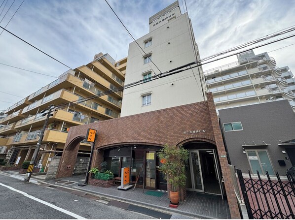 A multi-story building with a ground-level entrance, a brick facade, and a sign indicating a business. - Dai3kuboi 305 (Hiroshima)