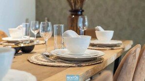 A dining table set with white bowls, wine glasses, and cutlery, with a rustic wooden table and woven placemats. - Maison La Roussette - in the heart of Nieuwpoort (Nieuwpoort)