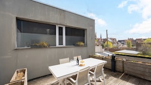 A modern building with a balcony featuring a table set for two, two potted plants, and a bottle of wine. - Maison La Roussette - in the heart of Nieuwpoort (Nieuwpoort)
