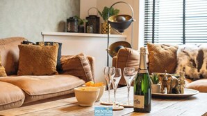 A cozy living room with a sofa, a table with a bottle of wine, glasses, and decorative items. - Maison La Roussette - in the heart of Nieuwpoort (Nieuwpoort)