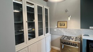 Een keuken met houten balken, een gasfornuis, een inbouwoven en een kast met glazen deuren.