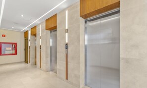 A modern elevator area with a clean, minimalist design, featuring a combination of wood and metal elements.