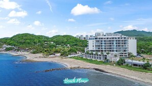 Un hotel frente al mar con varias plantas, una playa y abundante vegetación.