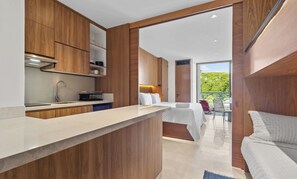 Una habitación de hotel moderna con kitchenette, una cama y vistas al exterior.