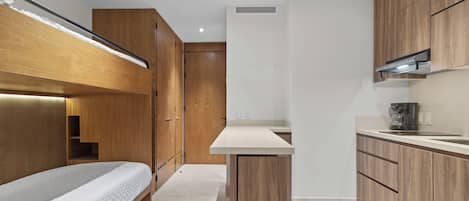 A compact bedroom with a bunk bed and a kitchenette area.