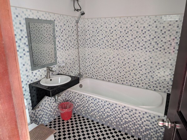 A bathroom with a white bathtub, a black sink, and a tiled wall with a mosaic pattern. - Tim & Sophy Angkor Inn (Siem Reap)