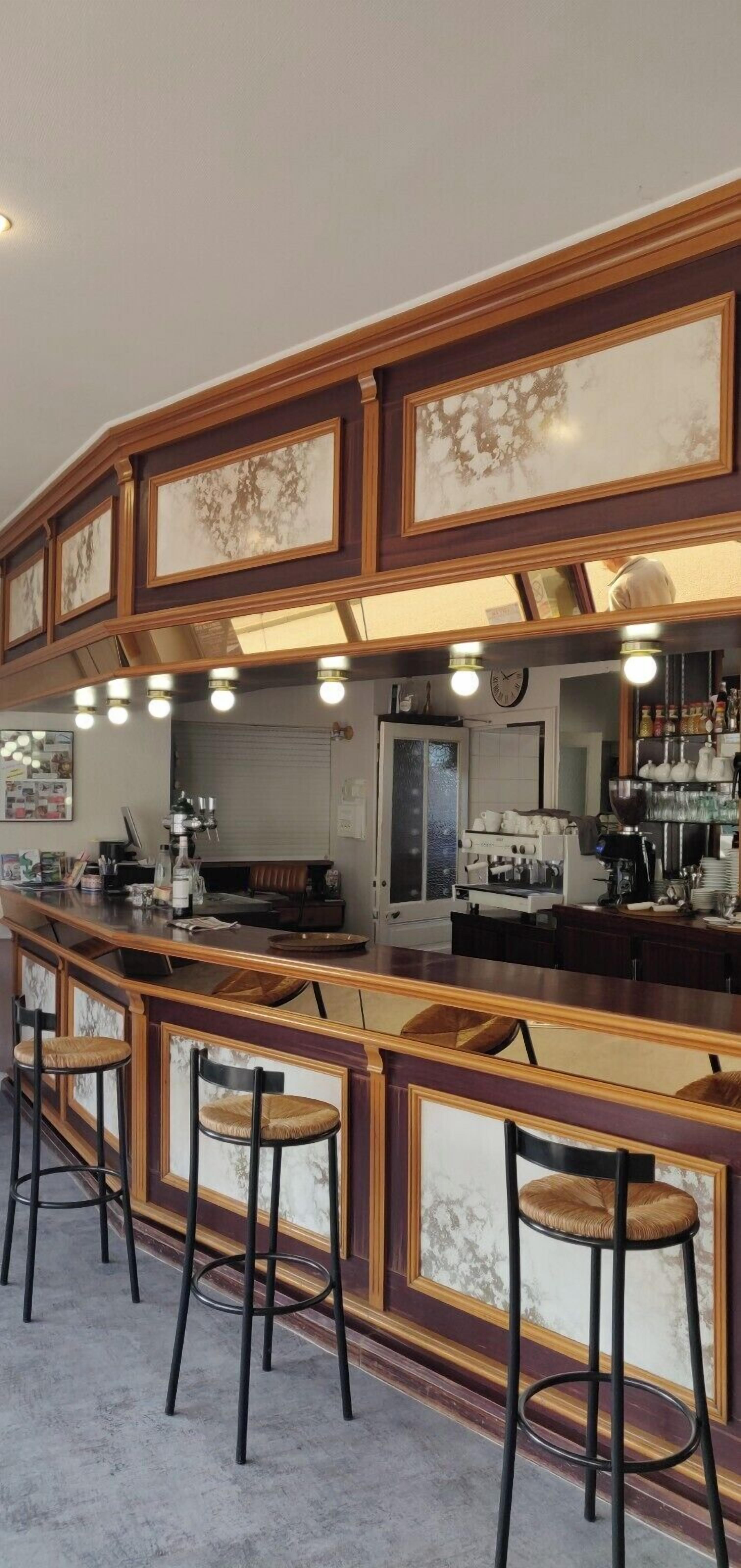 A bar area with a wooden counter, bar stools, and a coffee machine.