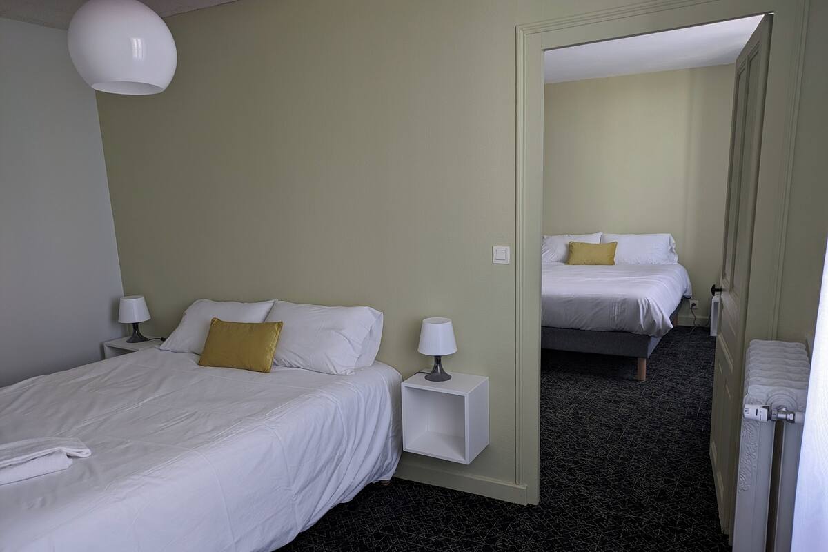 A hotel room with two beds, a mirror, a white lamp, and a patterned carpet.