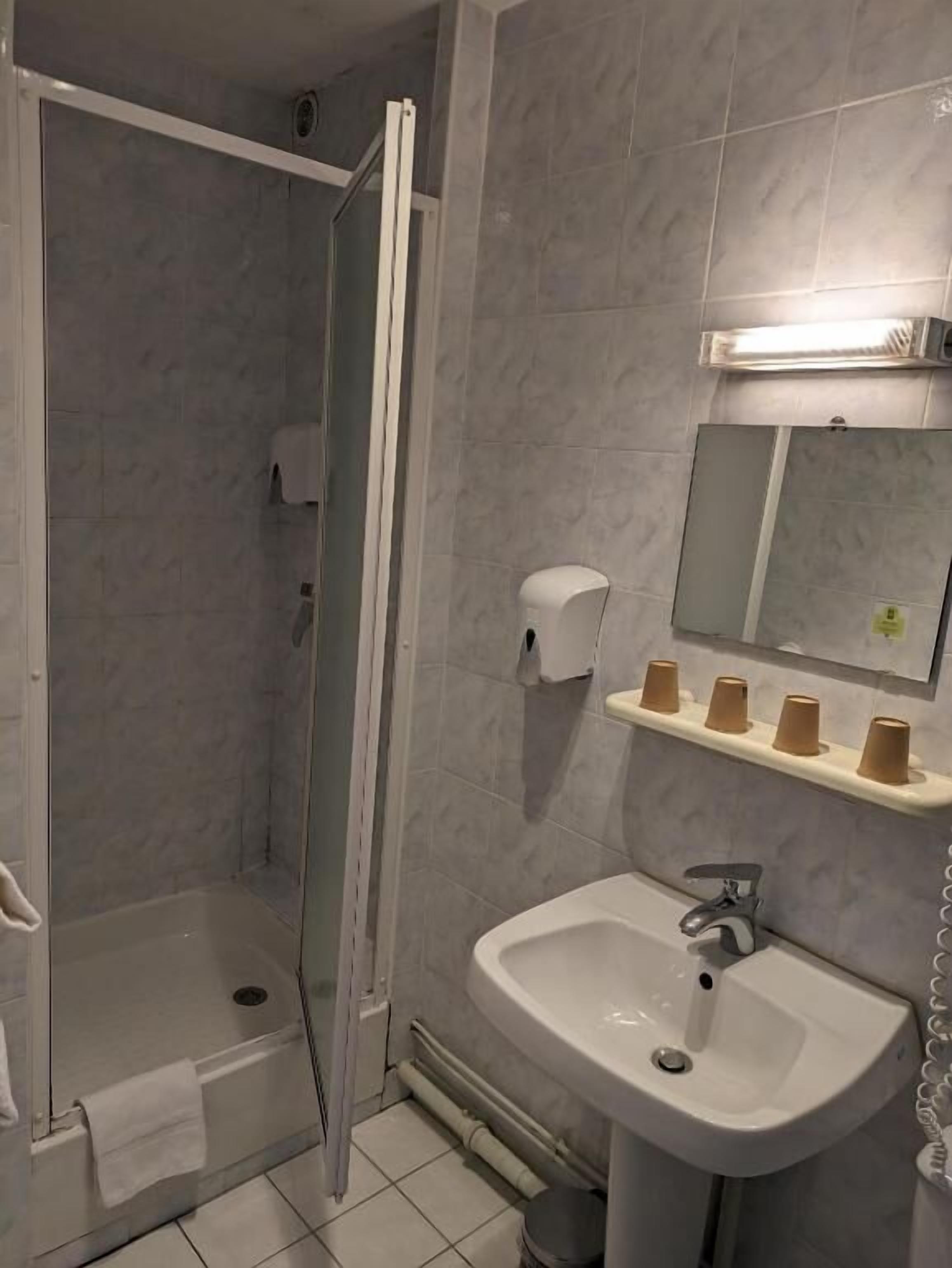 A bathroom with a shower, sink, and mirror.