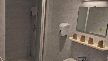 Un baño con ducha, lavamanos y espejo.