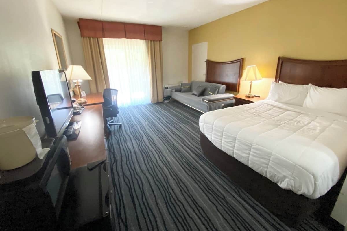 A hotel room with a bed, desk, chair, and a television.