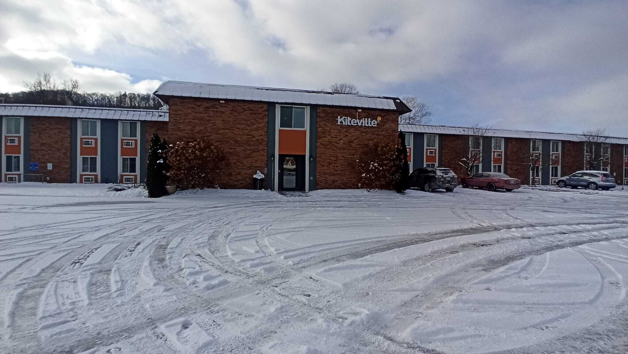 Ein Backsteinhaus mit einem Schild, auf dem „Kiteville“ steht, vor einem Parkplatz mit Schnee.
