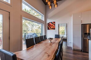 A modern kitchen with a large island, stainless steel appliances, and a dining area with a wooden table and chairs.