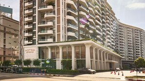 Un grand hôtel avec des balcons, une enseigne « ASTRA » bien visible et un ciel dégagé.