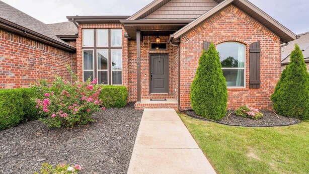 A brick house with a front porch, a window, and a door. - Modern 3BR Retreat • EV Charger • Fenced Yard by XNA (Cave Springs)
