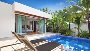 A modern poolside area with two lounge chairs, a clear blue pool, and a contemporary house with large glass doors.