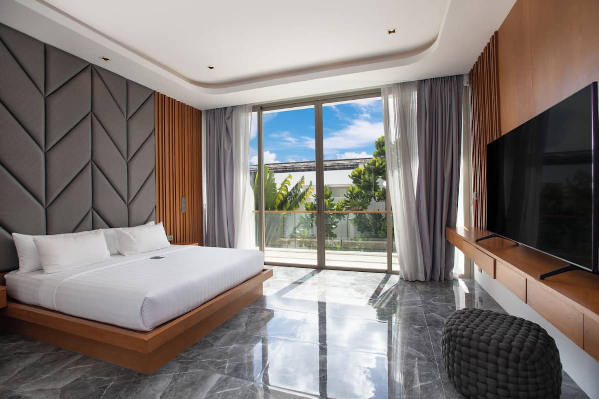 Quarto moderno com uma cama grande, TV e varanda com vista.