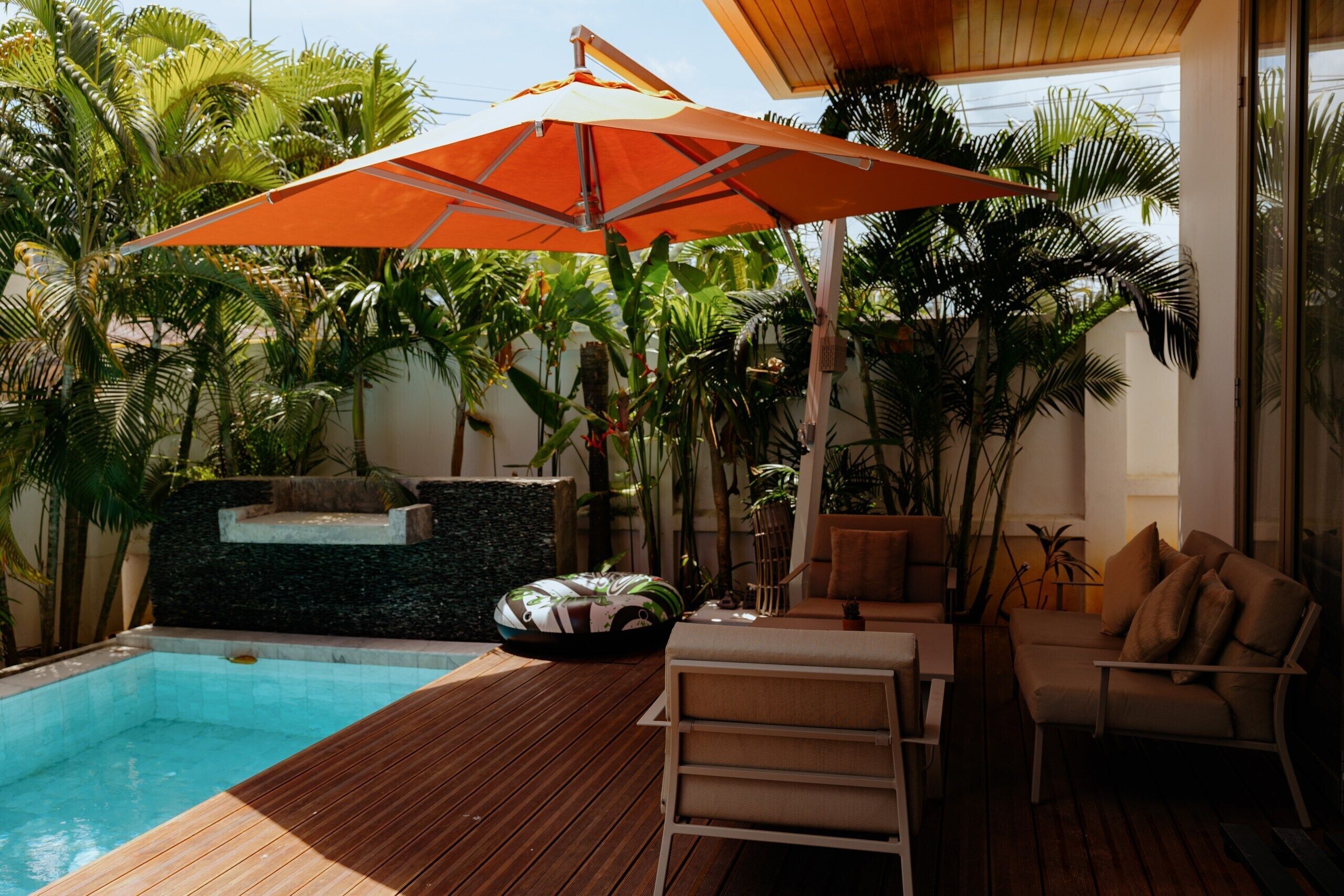 A wooden deck with a pool, a lounge chair, and an umbrella.