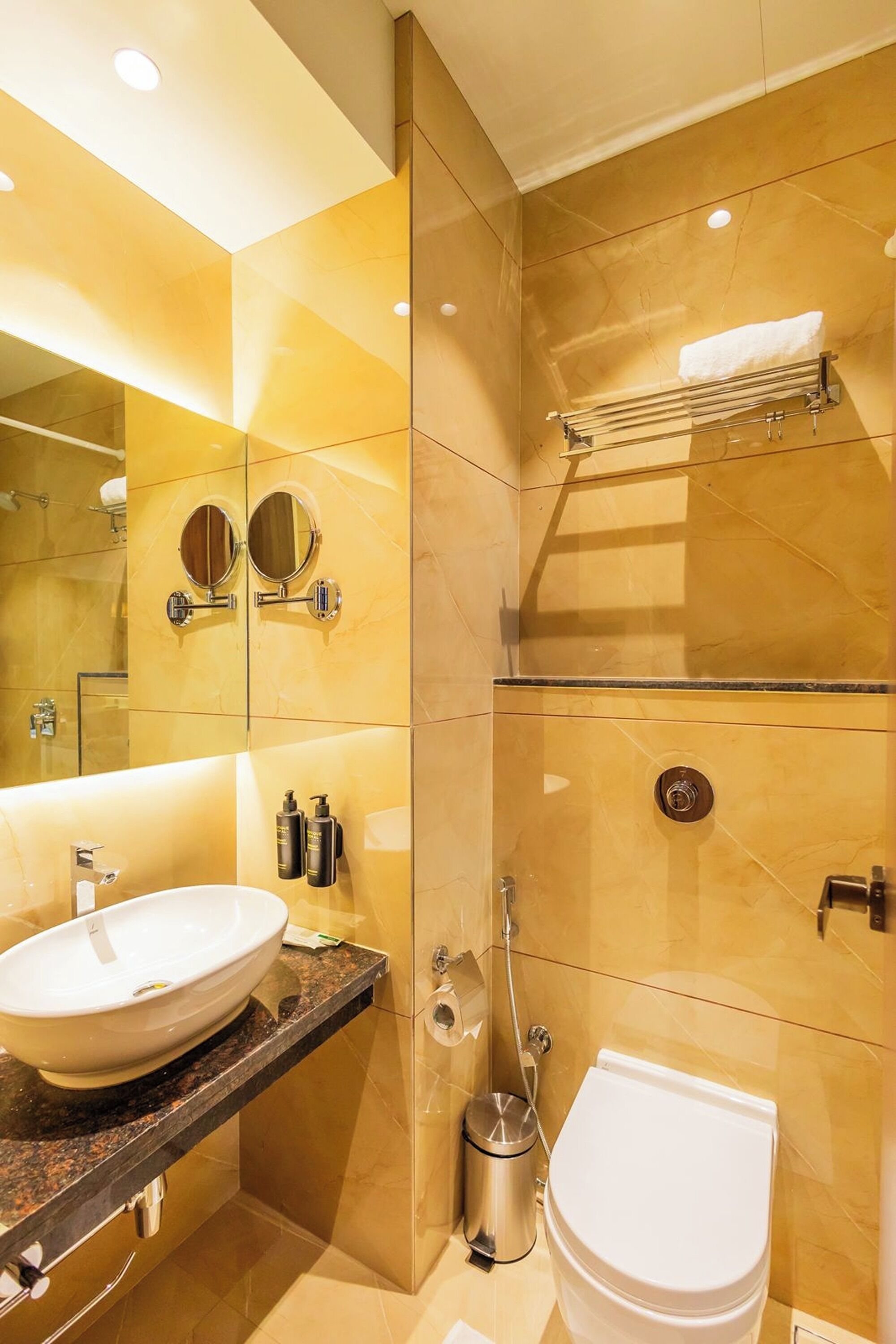 A modern bathroom with a large mirror, a sink, and a toilet.
