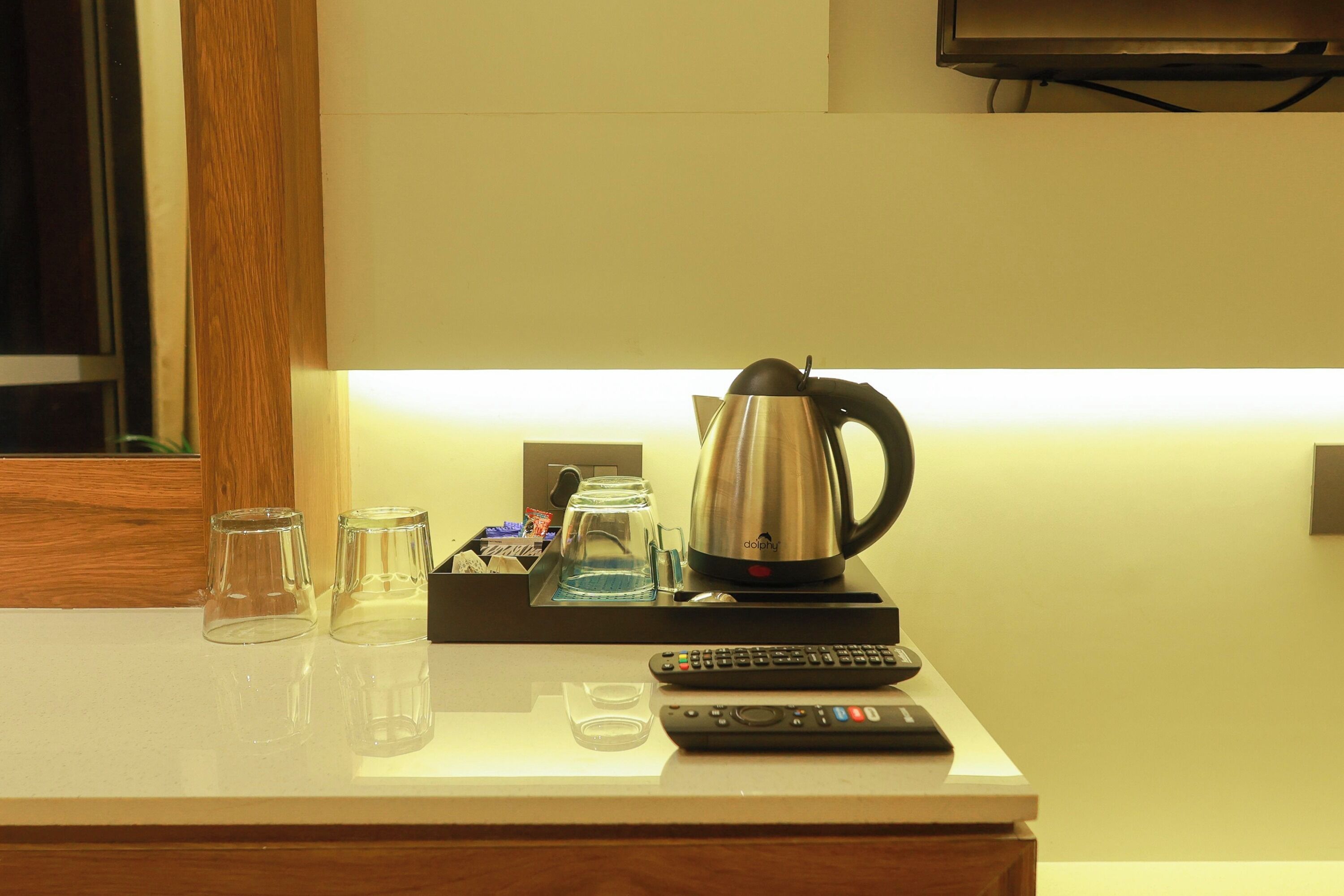 Ein Hotelzimmer mit einer Kaffeemaschine, Gläsern und einer Fernbedienung auf der Ablagefläche.
