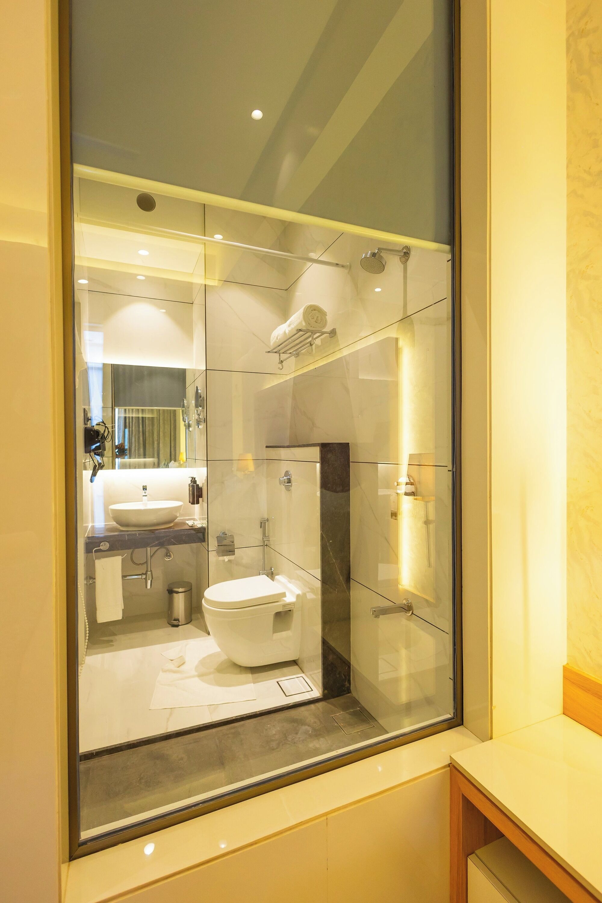 A modern bathroom with a glass enclosure, a sink, a toilet, and a shower area.