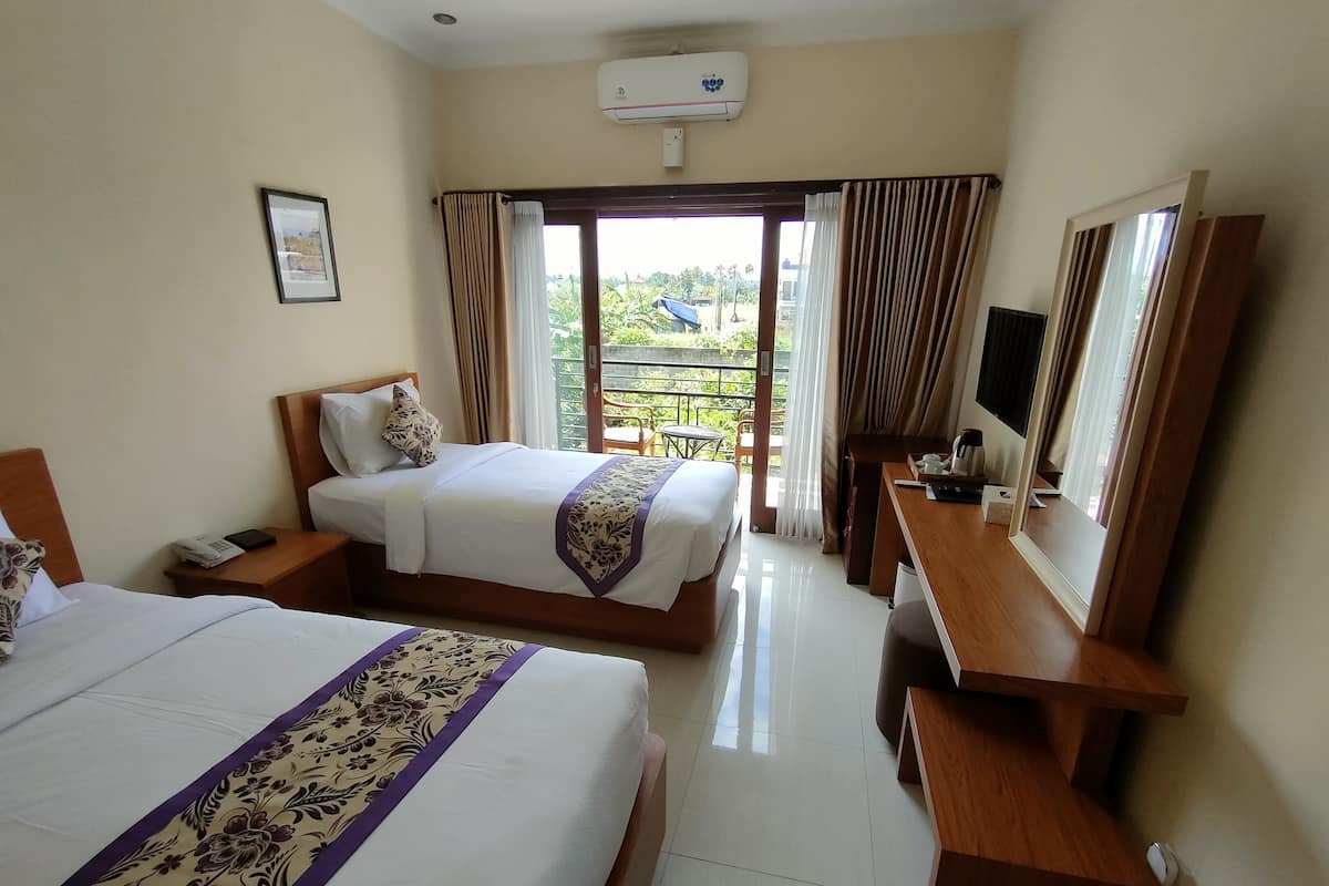 A hotel room with two beds, a desk, a TV, and a balcony with a view.