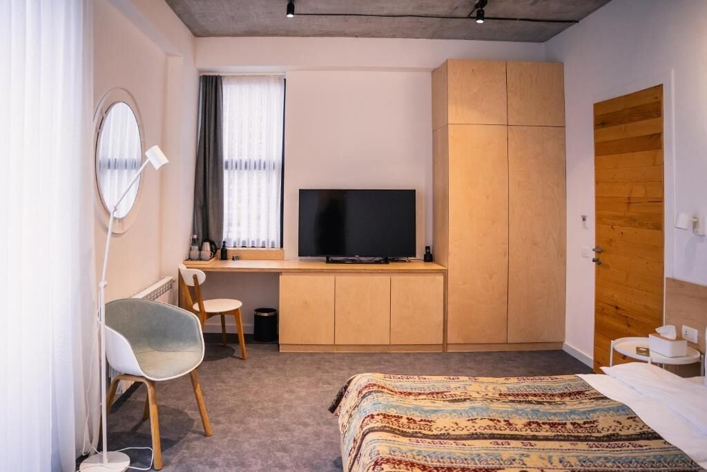 Un dormitorio con cama, escritorio con televisor, silla y armario.