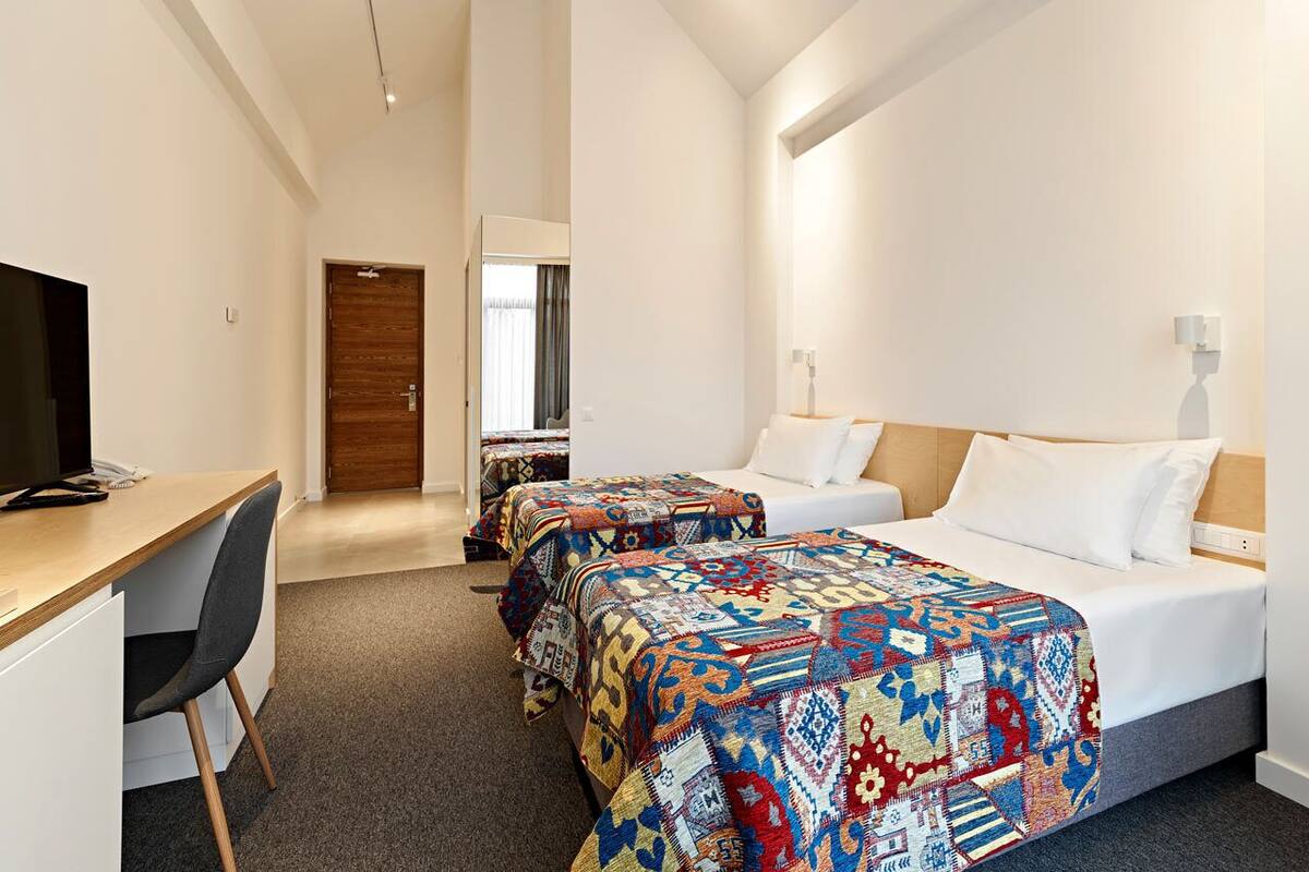 Ein Hotelzimmer mit zwei Betten, einem Schreibtisch und einem Fernseher.