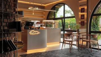 A cafe interior with a modern design, featuring a counter with a neon sign, seating area, and large windows.