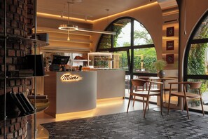A cafe interior with a modern design, featuring a counter with a neon sign, seating area, and large windows. - Dilijani Tun (Dilijan)