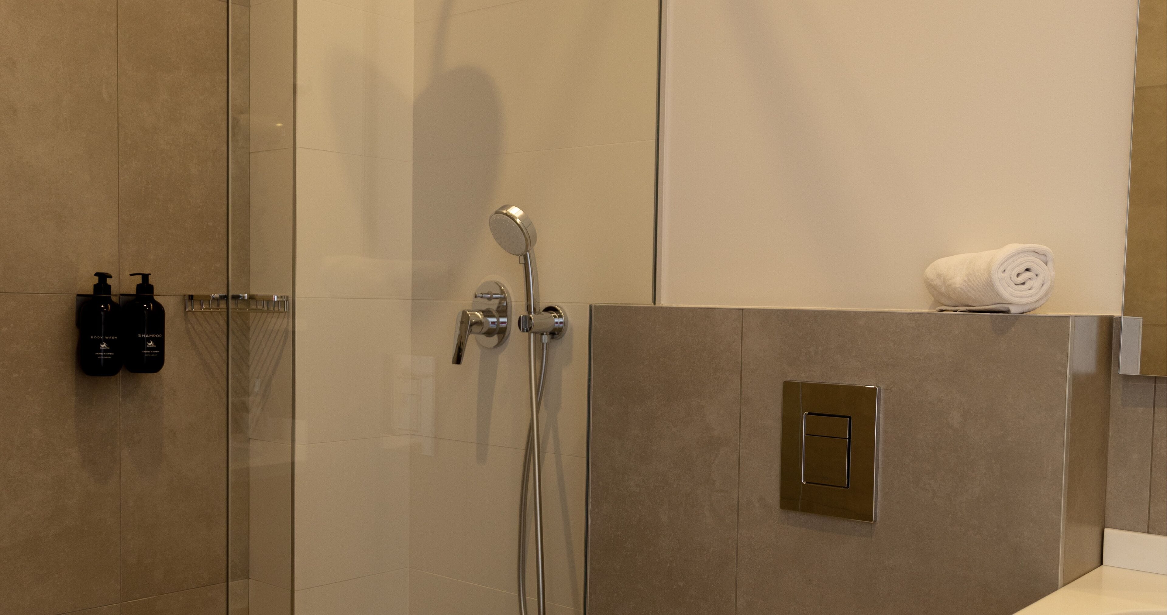 Un baño moderno con cabina de ducha de vidrio, un perchero y un toallero empotrado.