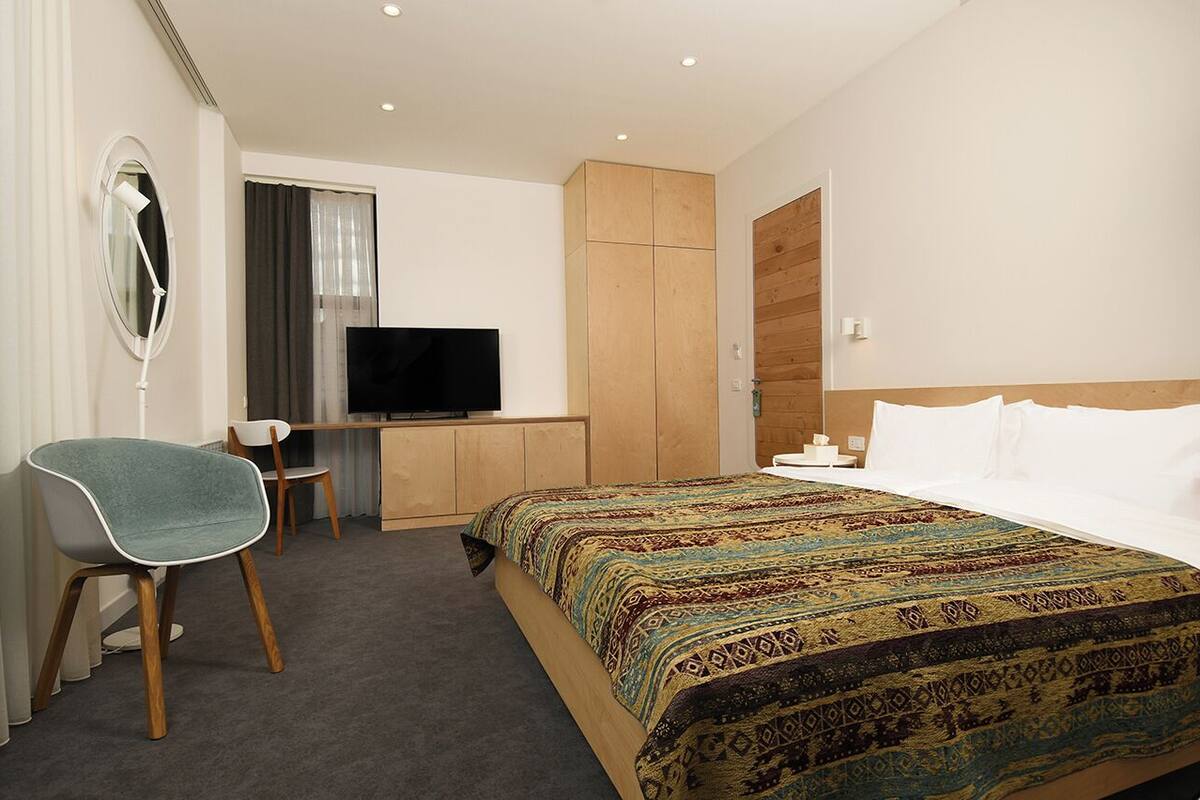 Ein Hotelzimmer mit Bett, Schreibtisch, Stuhl, Fernseher und Kleiderschrank.